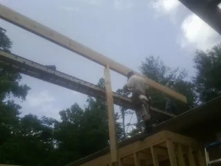 Carpenter setting a ridge beam over a new addition frame — Ice Dam Removal by Roofing Brothers in Leakey