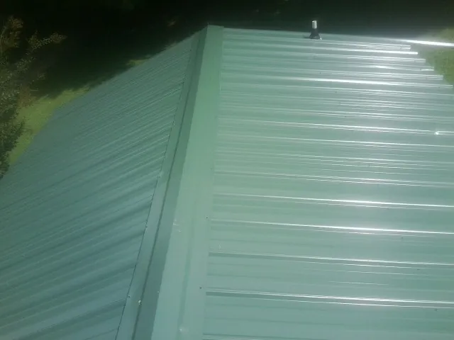 New green metal panels meeting at the ridge of a roof — Flat Roof Repair work by our crew in Leakey