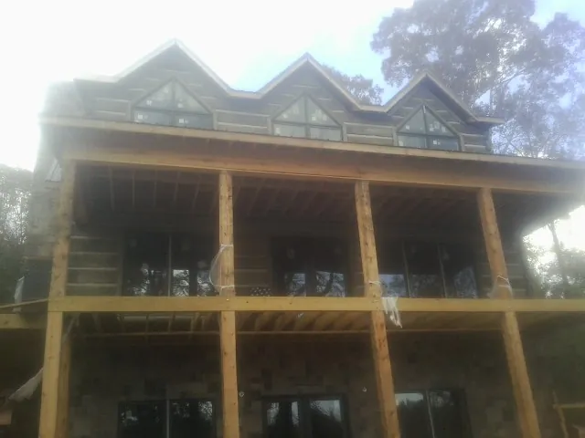 Dormers and porch framing on a large log home under construction — Roof Coating work by our crew in Leakey