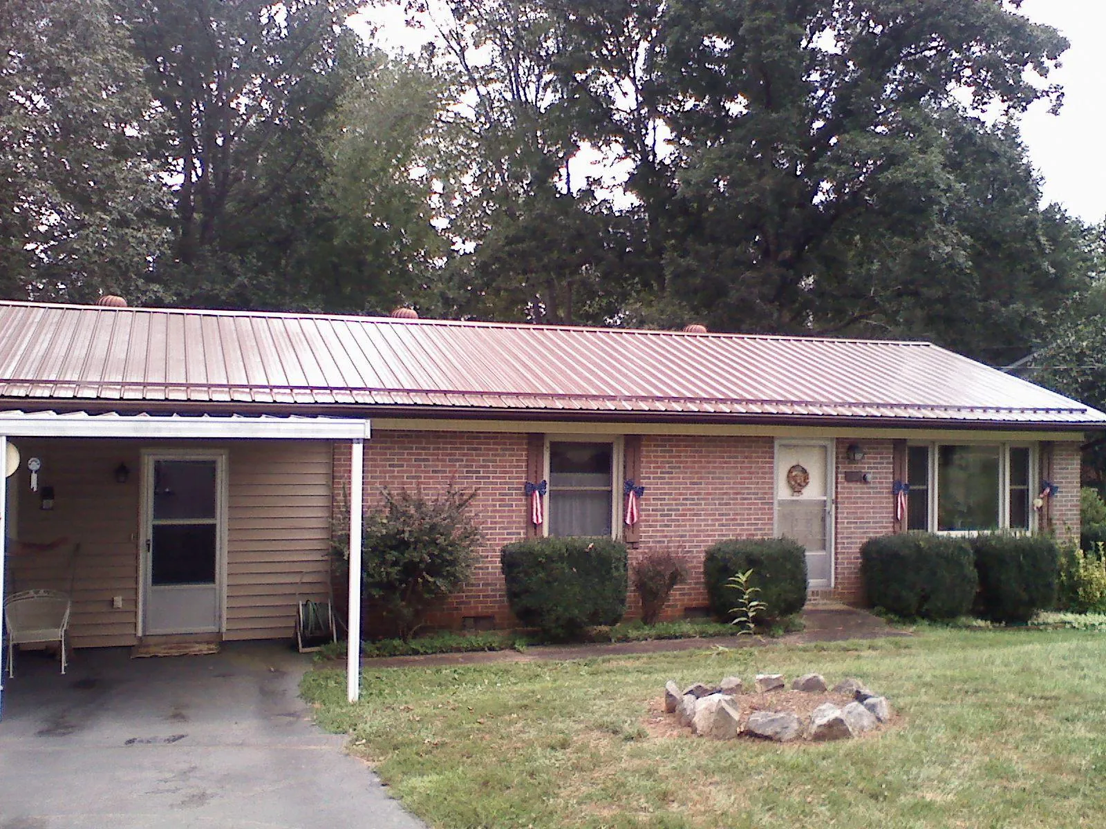 Bronze metal roof and carport on a brick ranch home — Roof Repair work by our crew in Leakey