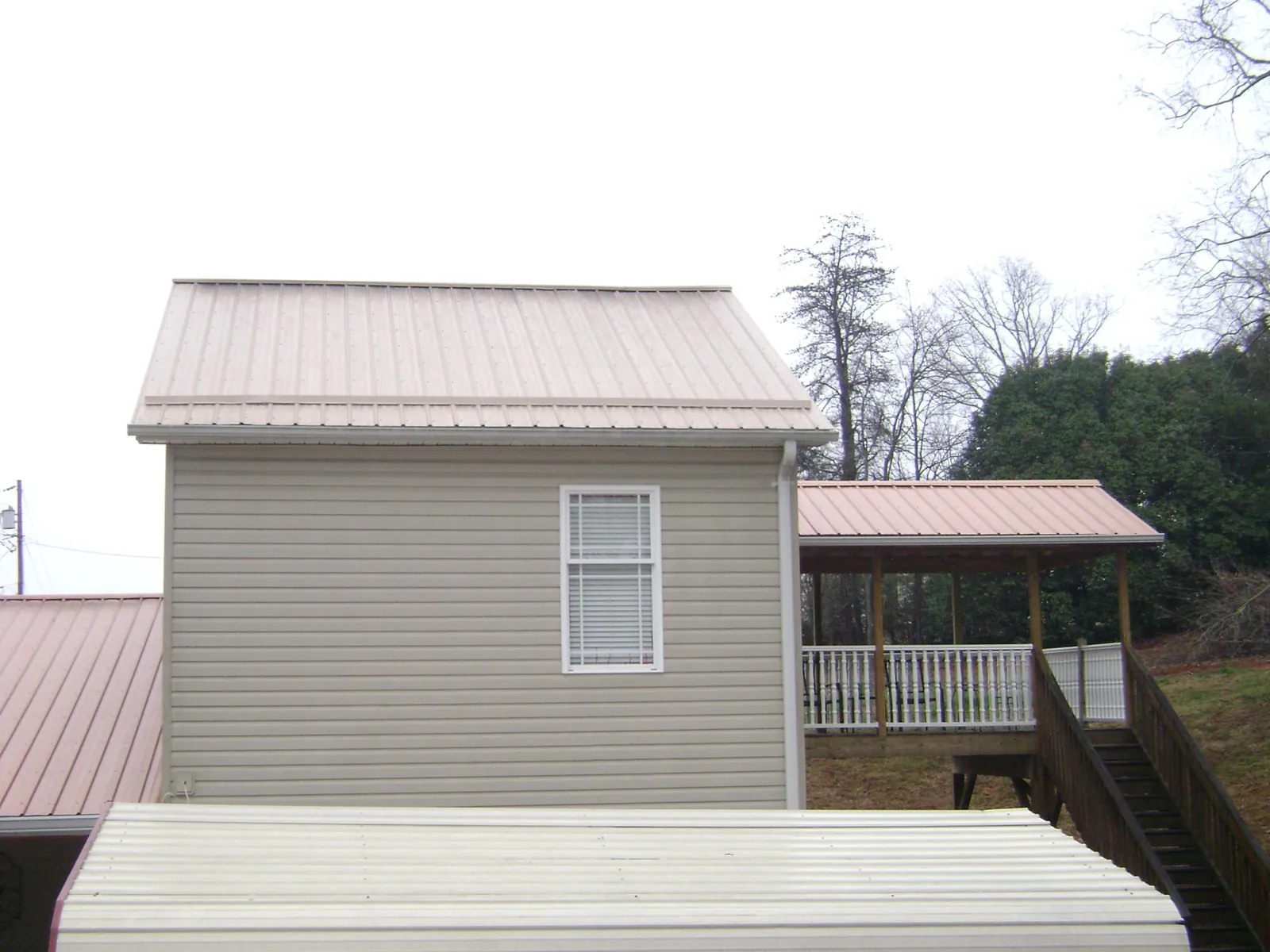 Tan metal roofs on a two story addition and attached porch in Leakey