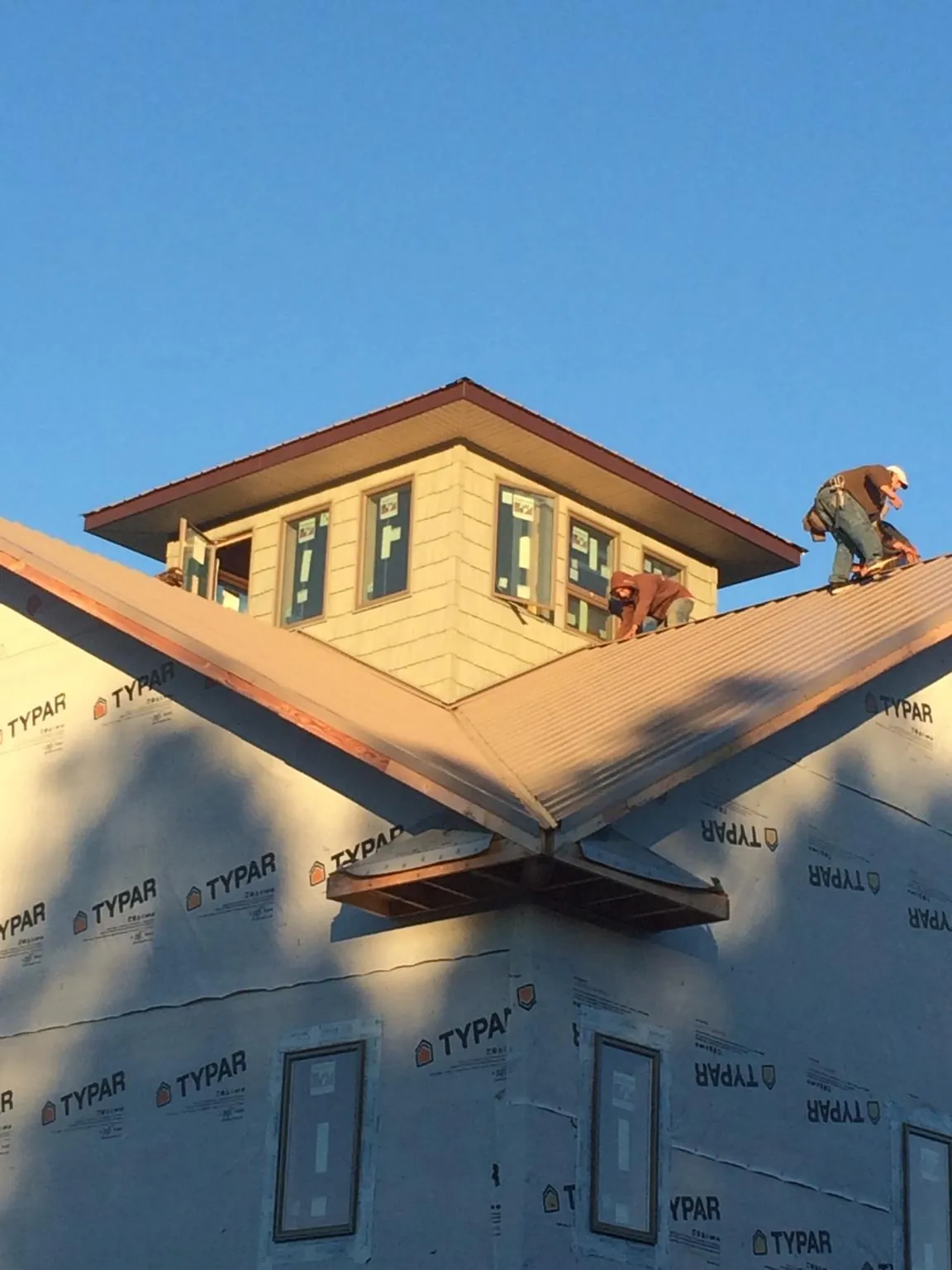 Roofers working around a rooftop cupola on a new metal roof at sunset — Roof Waterproofing in Leakey by Roofing Brothers
